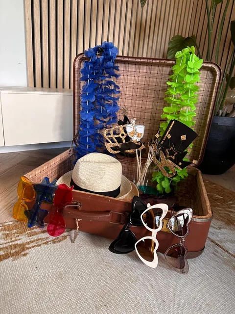 Vintage koffer met props: hoed, brillen, bloemenkransen en borden